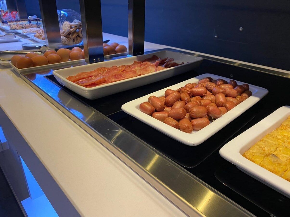 A buffet with trays of eggs, bacon, peanuts, and a dish of scrambled eggs.