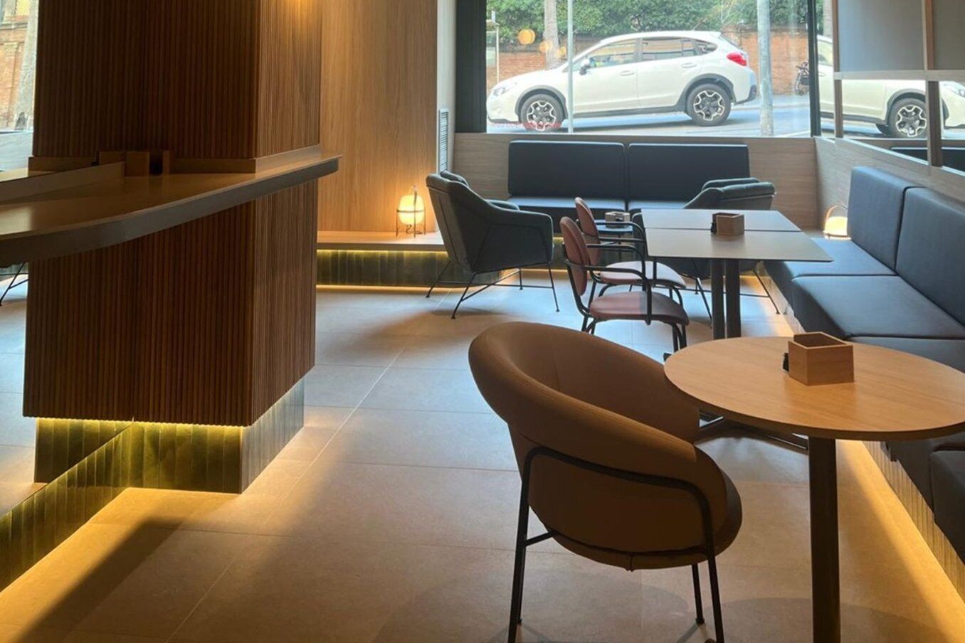 Un interior moderno con una zona de estar, un muro de acento de madera y vista a la calle.