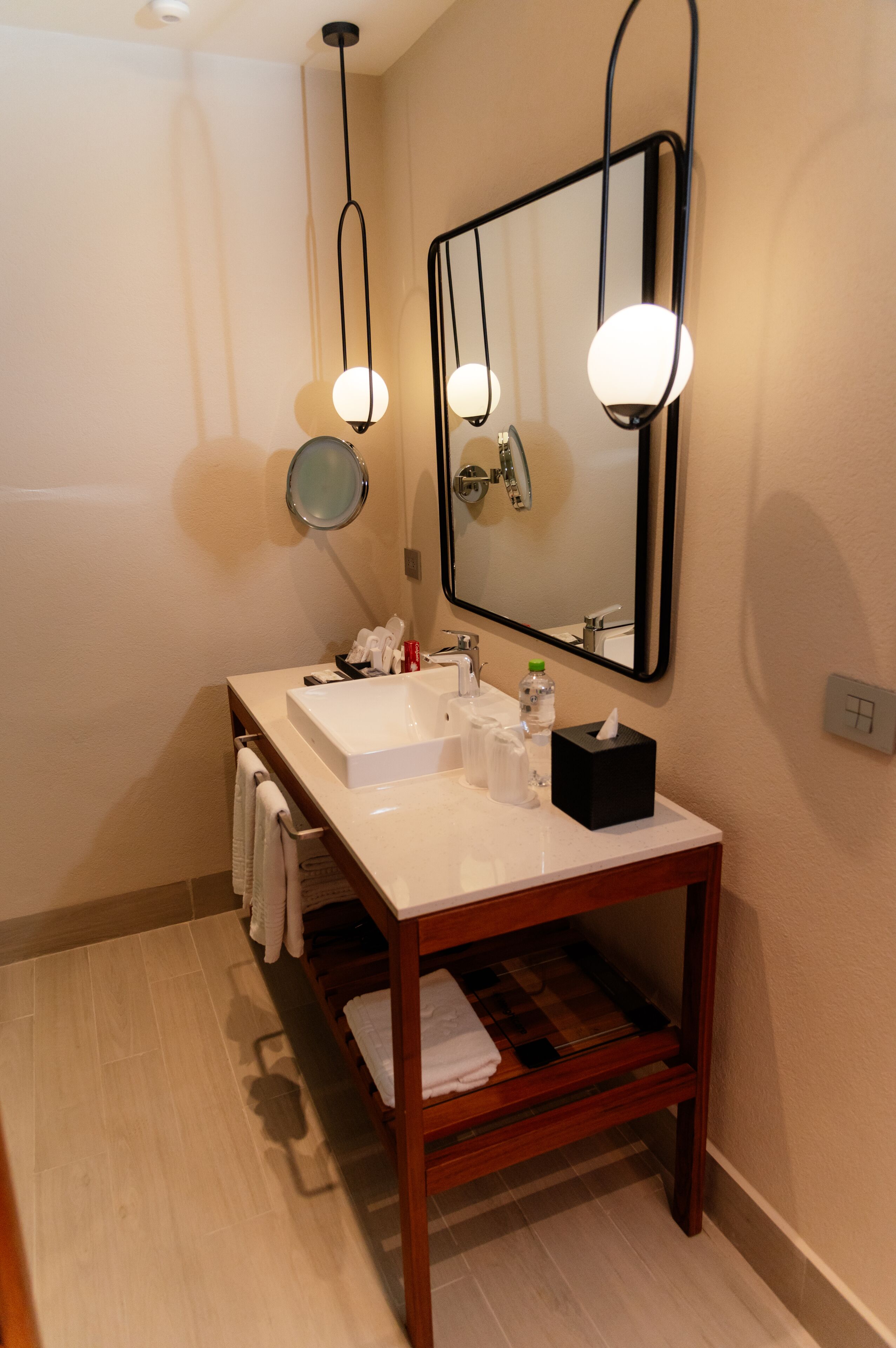 Une salle de bain moderne avec un meuble-lavabo en bois, un grand miroir et un lavabo blanc.