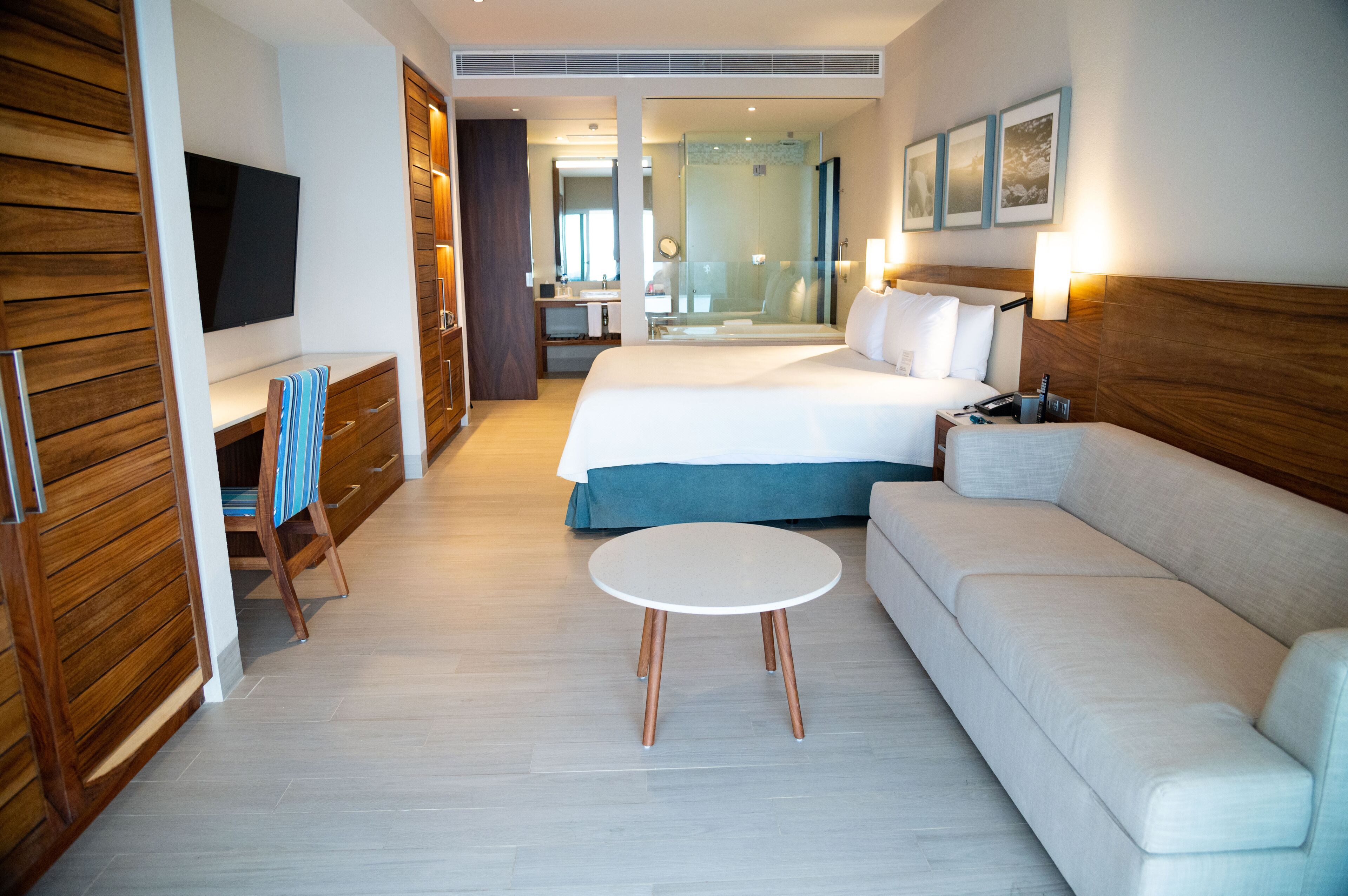 Una habitación de hotel con cama, sofá, televisor, escritorio y espejo.
