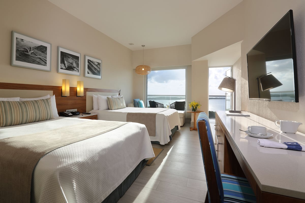 Habitación de hotel con una cama grande, un escritorio, una silla y vistas al mar.