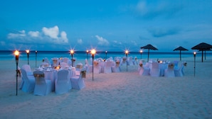 A beachside dining setup with tables and chairs, arranged for a meal. - Emporio Cancun Optional All Inclusive (Cancun)