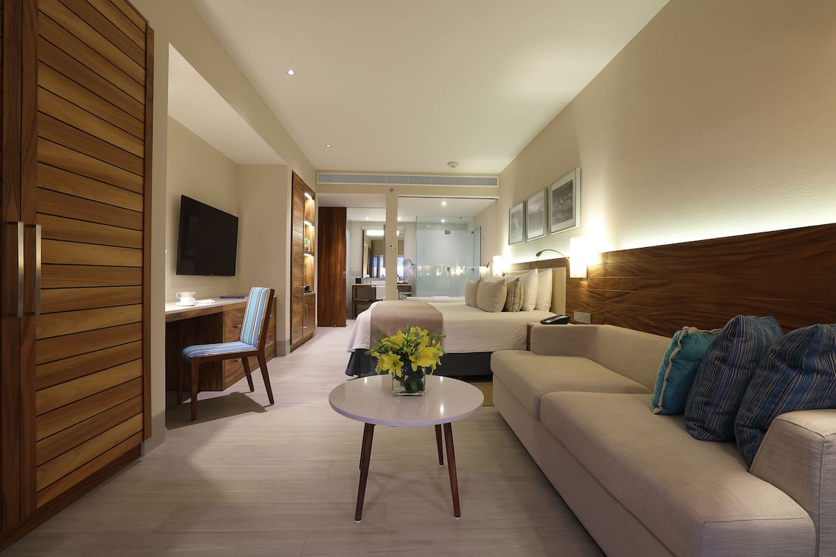 Una habitación de hotel con cama, sofá, televisión, escritorio y silla.