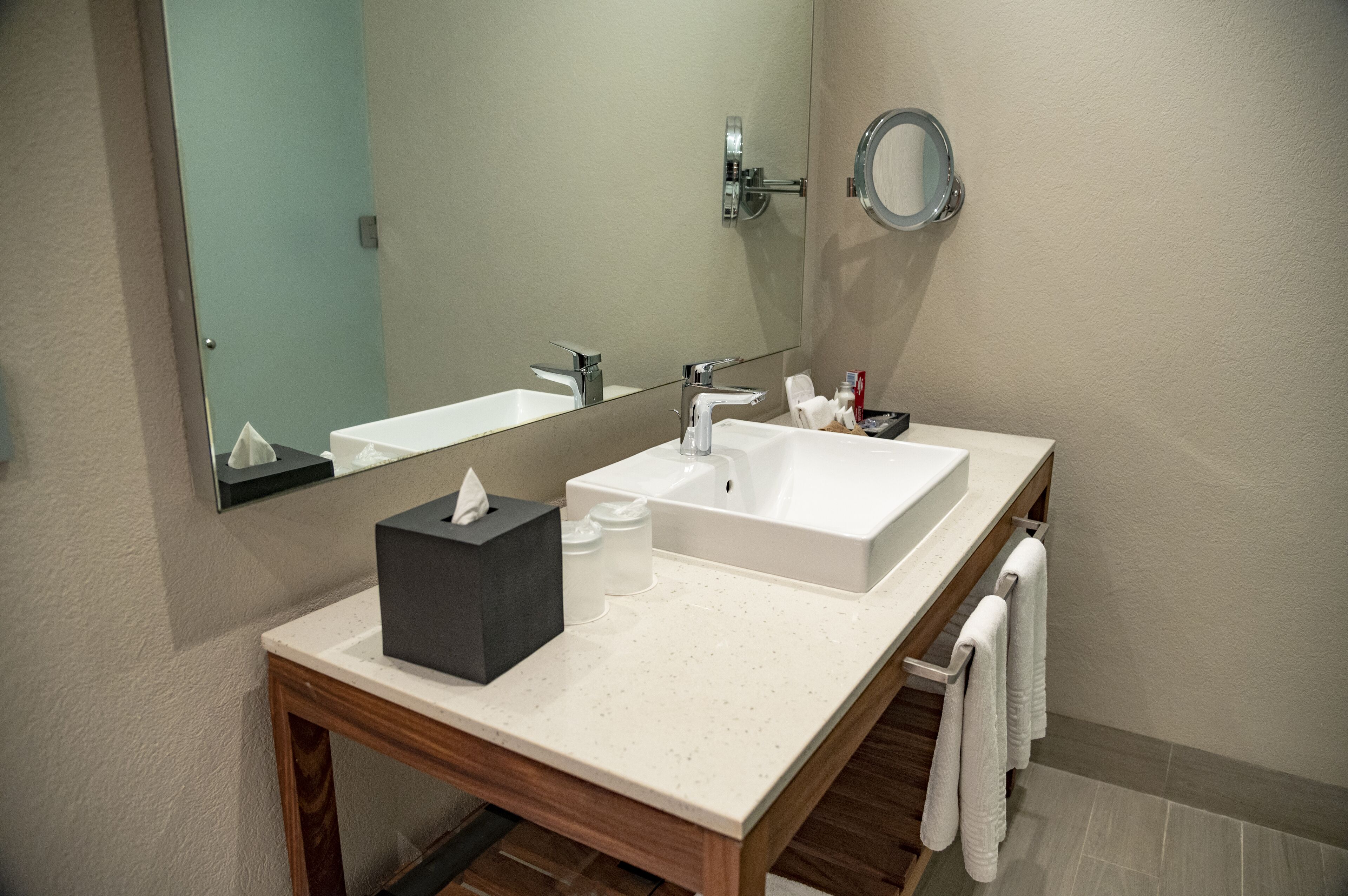 Un bany modern amb un doble lavabo, un mirall, una barra de tovalloles i una petita taula amb productes de tocador.
