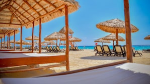 A beach with thatched umbrellas and lounge chairs. - Emporio Cancun Optional All Inclusive (Cancun)