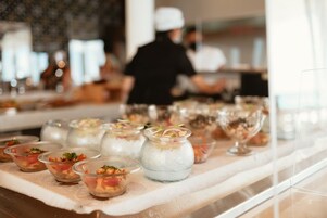 Una mesa de buffet con diversos platos, incluyendo recipientes transparentes con comida y un tarro de vidrio con un líquido azul.
