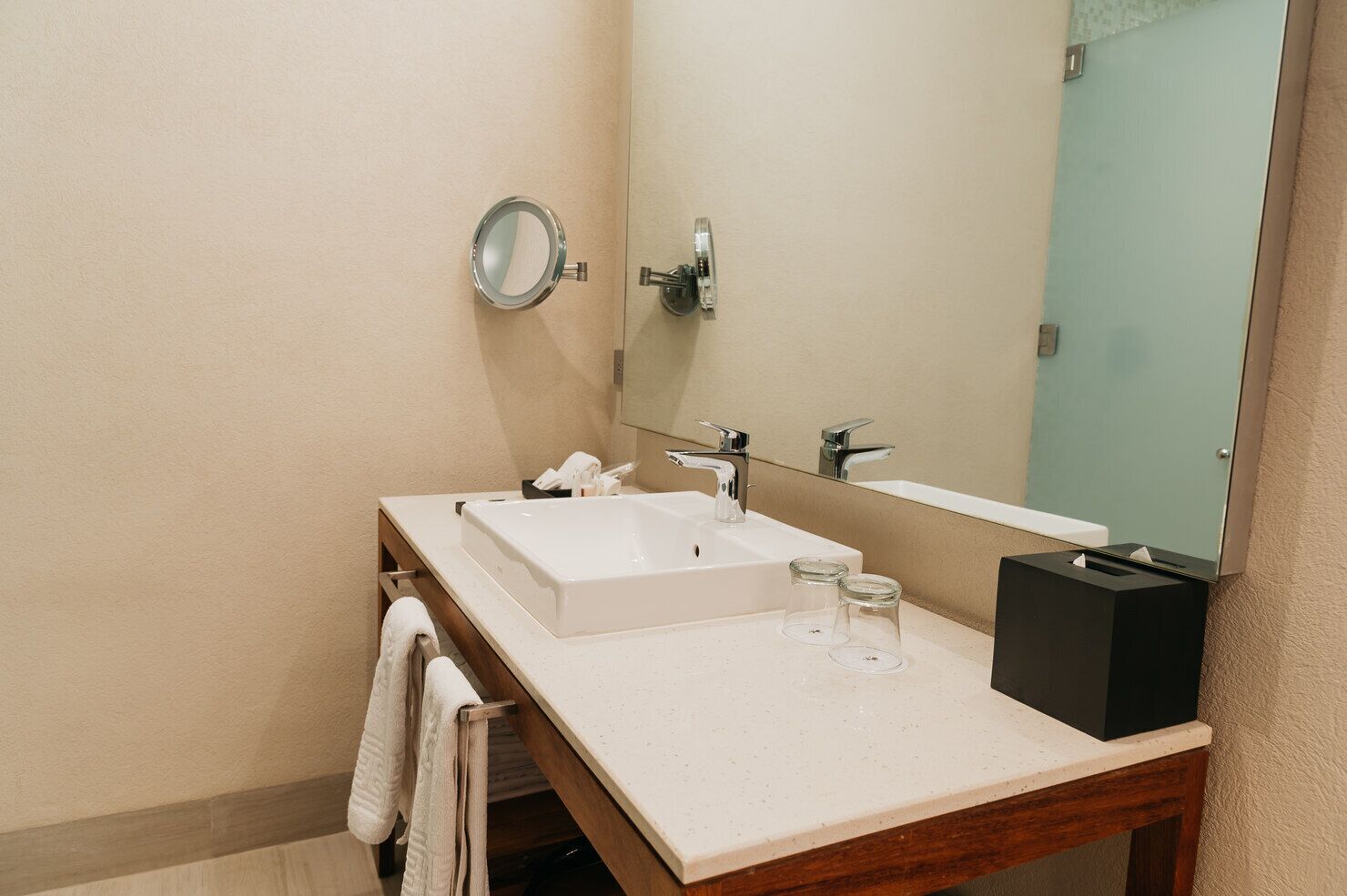 A bathroom with a white sink, a mirror, and a towel rack.