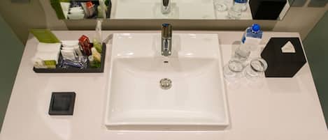 A hotel bathroom with a white sink, mirror, and toiletries.