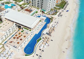 Vista aérea de un resort con una piscina grande, playa y varios edificios.