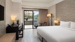 A hotel room with a bed, desk, chair, and a view of the outdoor area. - Grand Mercure Singapore Roxy (Singapore)