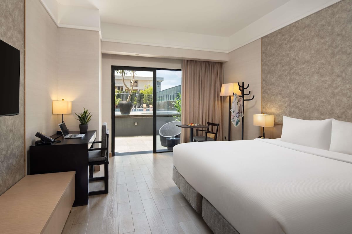 Habitación de hotel con cama, escritorio, silla y vistas al exterior.