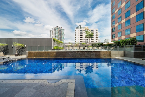 Una piscina al aire libre, sombrillas, sillones reclinables de piscina