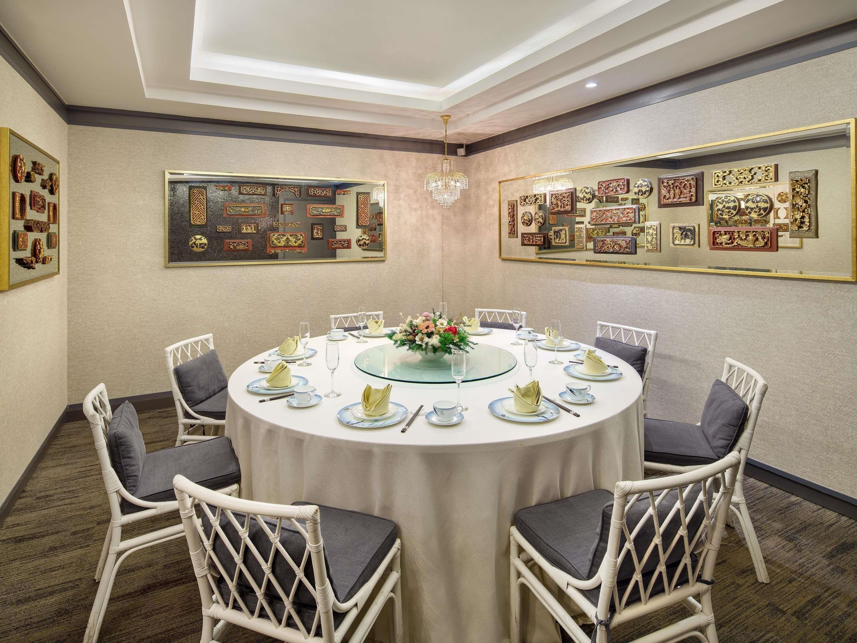 A conference room with a round table, white wicker chairs, and framed artwork on the walls.