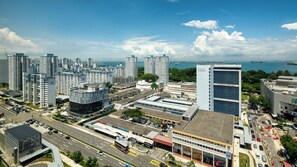 Área urbana com arranha-céus, edifícios modernos, um círculo de rotatórias e vista para o mar.
