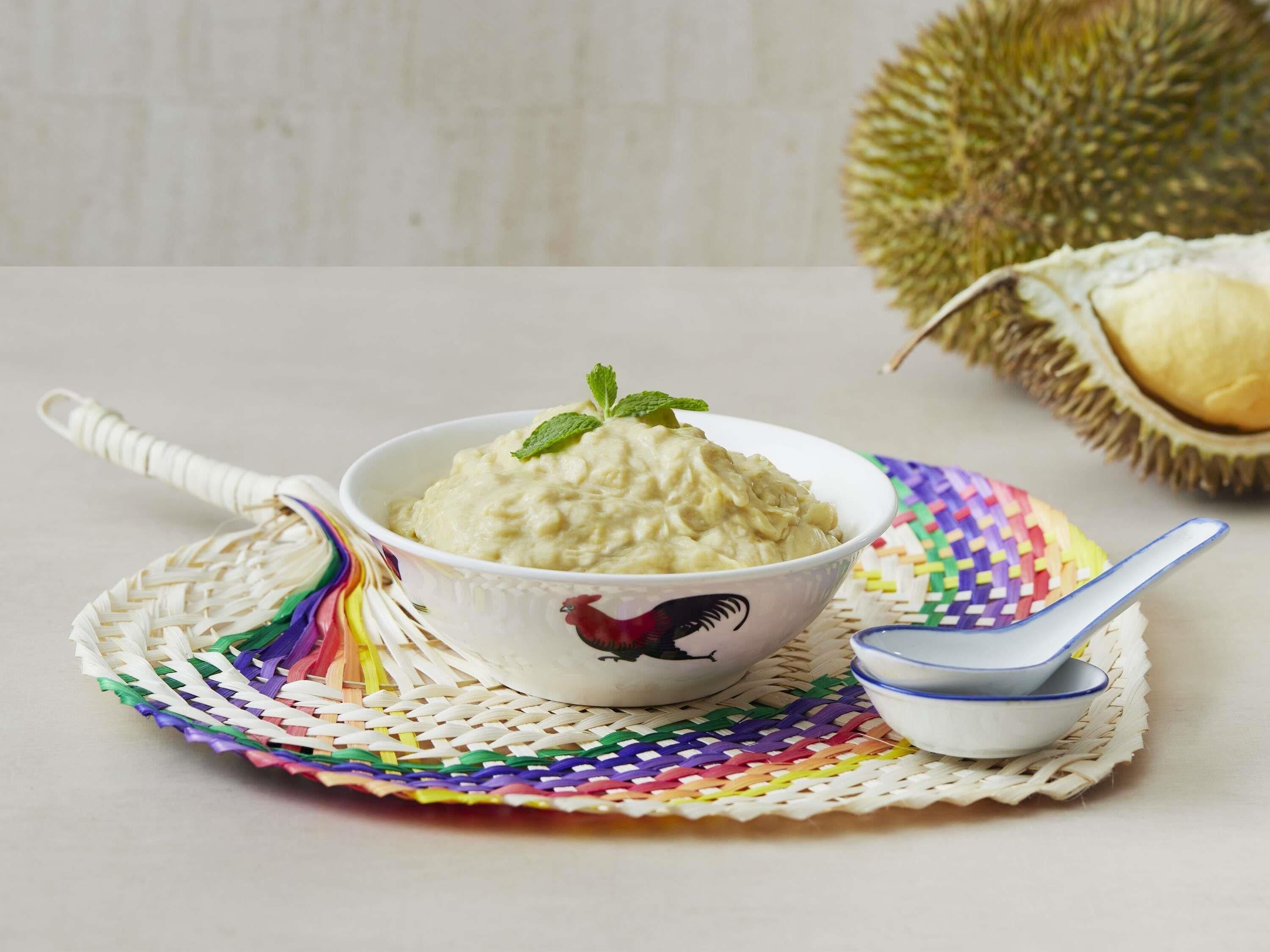 Un plato de comida sobre un tapete tejido, junto a una cuchara y un recipiente pequeño.