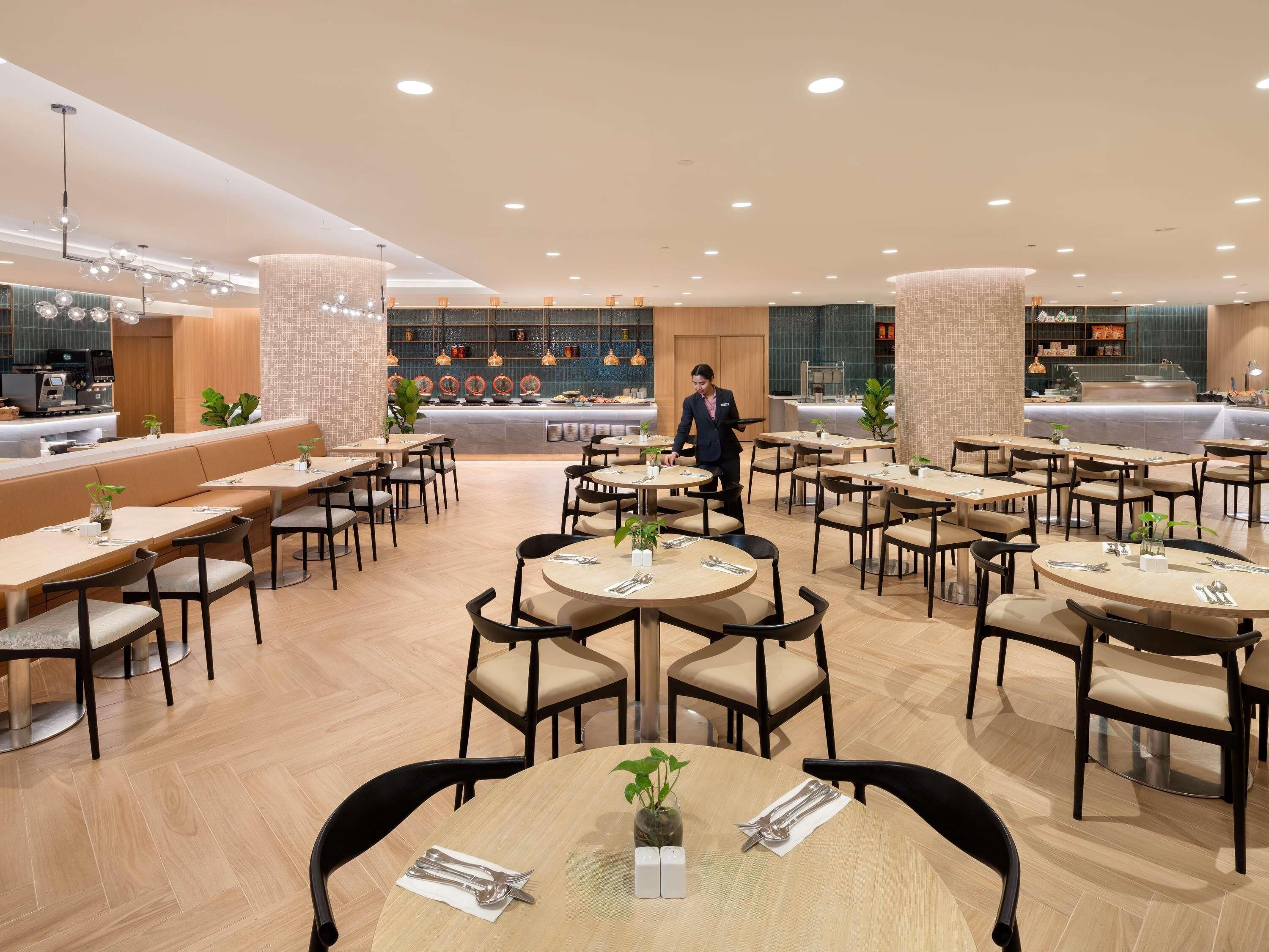 Un restaurante moderno con mesas redondas, una zona de bar y un área de estar.