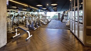 A gym with exercise equipment, wooden flooring, and large windows. - Grand Mercure Singapore Roxy (Singapore)