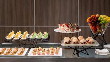 A buffet with various food items, including sandwiches, desserts, and fruit.