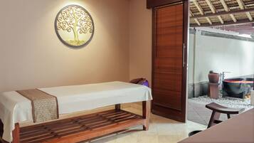 A room with a wooden bench, a wall-mounted light fixture, and a view of a spa area with a hot tub.