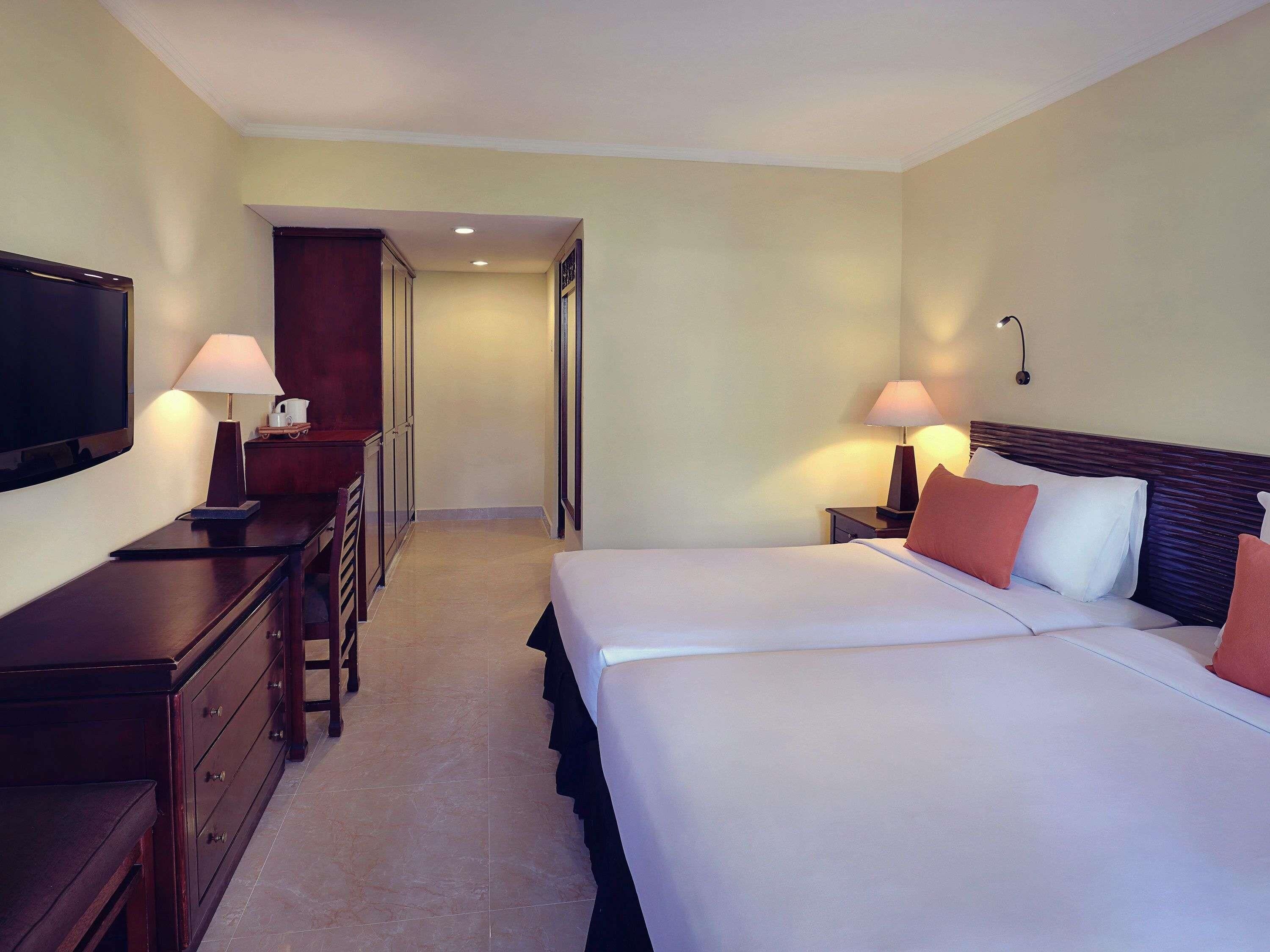 A hotel room with a large bed, a TV, a desk, and a wardrobe.