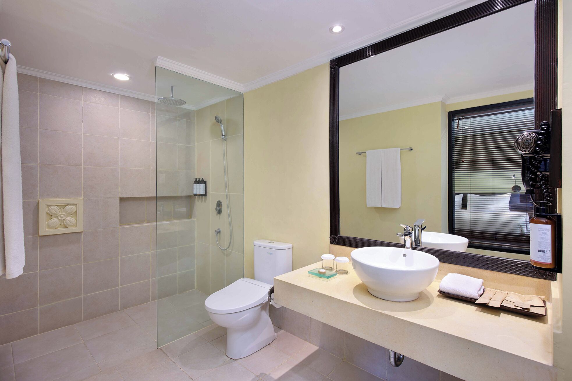 A modern bathroom with a glass-enclosed shower, a white toilet, a large sink with a mirror, and a towel rack.