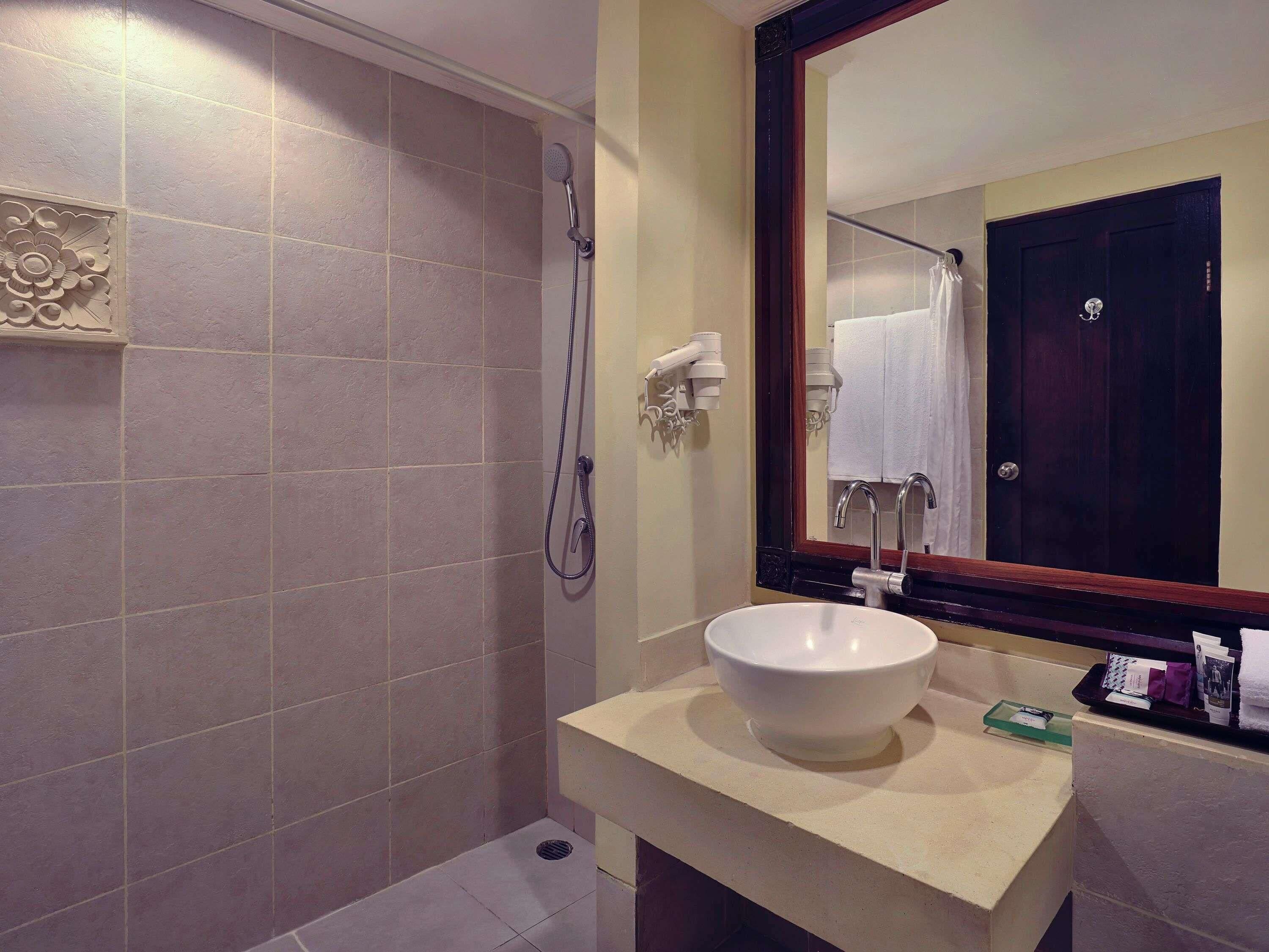 A bathroom with a shower, a sink, a mirror, and a towel rack.