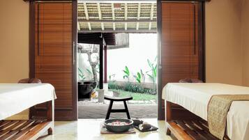 Two comfortable beds with white bedspreads and brown headboards, a small stool, and a wooden floor.
