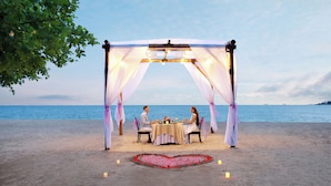 Un entorno de playa con una tolda y una disposición de velas con forma de corazón.