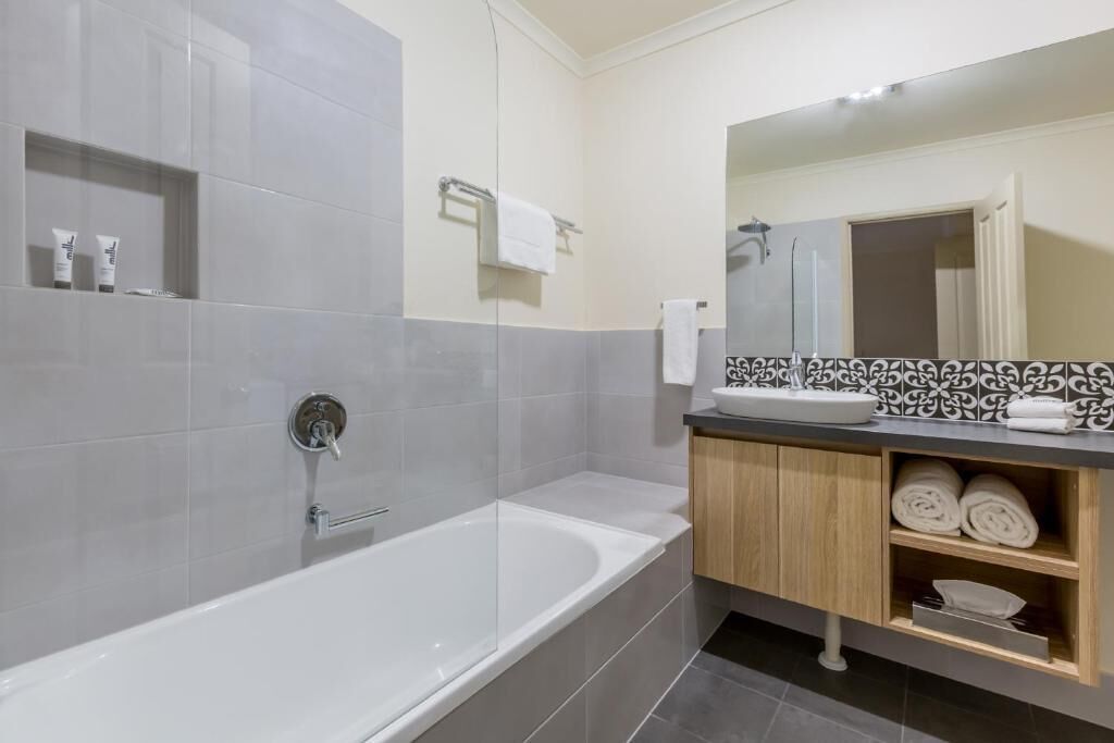 A modern bathroom with a large bathtub, a vanity with a mirror, and a shower area.