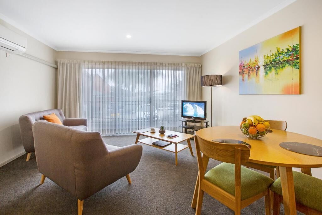 A living room with a sofa, a coffee table, a TV, and a painting on the wall.