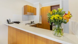Una cocina moderna con armarios de madera, una encimera blanca y un florero sobre la encimera.