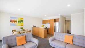 Un apartamento moderno con dos sofás grises, una isla de cocina de madera y un comedor.