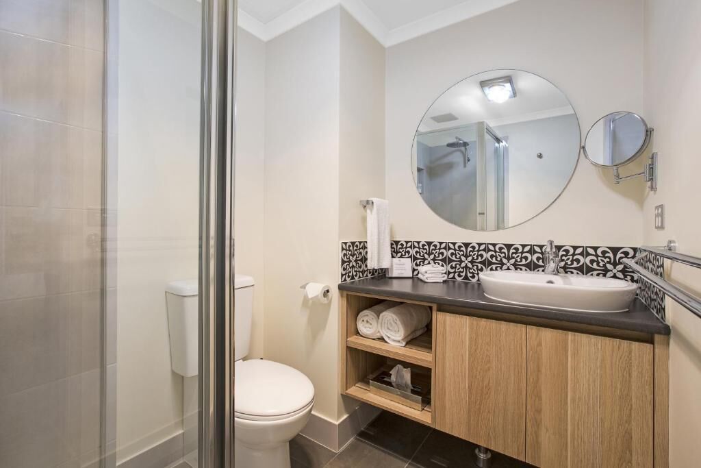 Une salle de bain avec des toilettes, un lavabo et deux miroirs.
