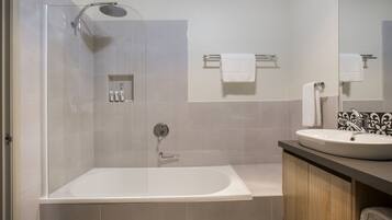 Et moderne badeværelse med et glasafskærmet brusebad, et fristående badekar og en vaskebord med håndvask.
