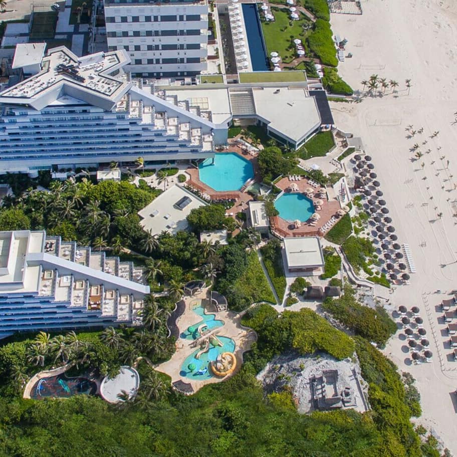 A resort with multiple swimming pools, a beach, and a large hotel structure.