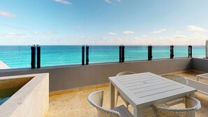 A terrace with a view of the ocean, featuring a table and chairs, and a concrete planter. - Park Royal Beach Cancun - All Inclusive (Cancun)