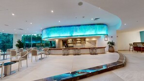 A modern bar area with a curved counter, bar stools, and a view of the outdoors.