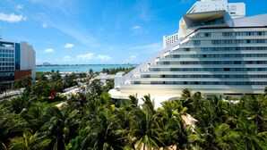 A modern hotel with a curved facade, a pool area, and a view of the ocean. - Park Royal Beach Cancun - All Inclusive (Cancun)