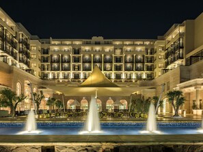 Un hotel de varios pisos, con terraza y una fuente.