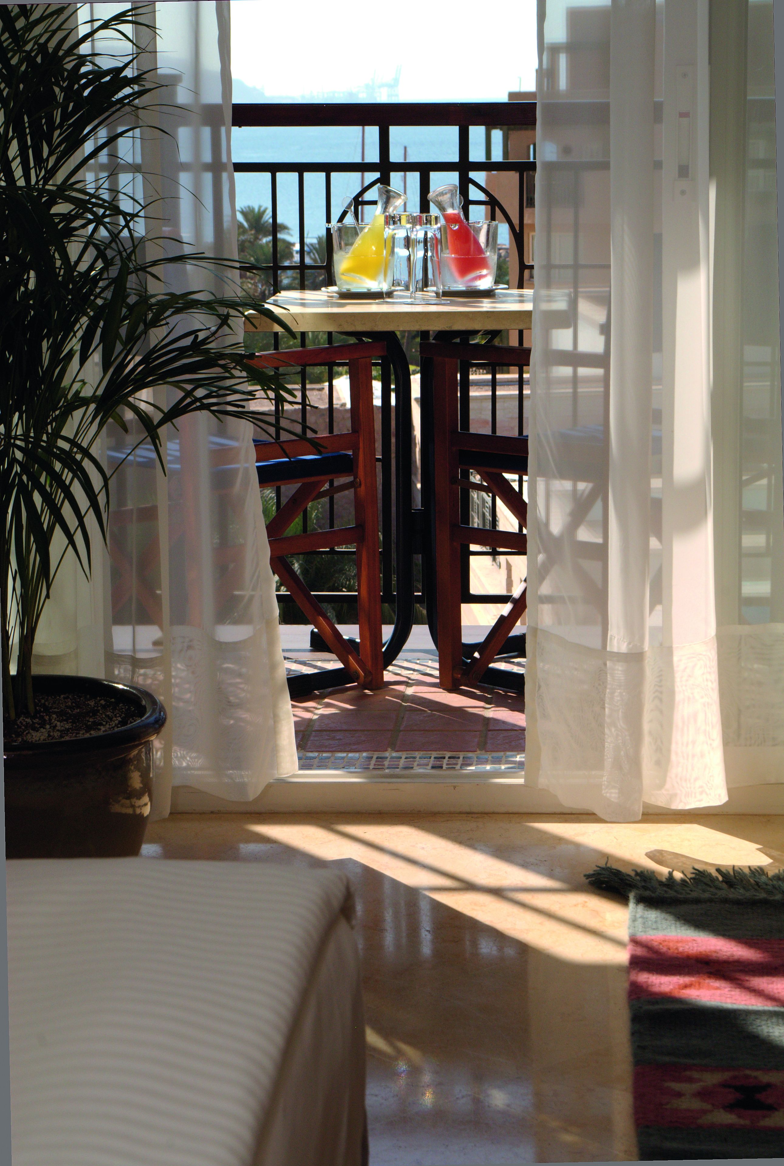 Un balcon avec une table, des chaises et un pot de fleurs.