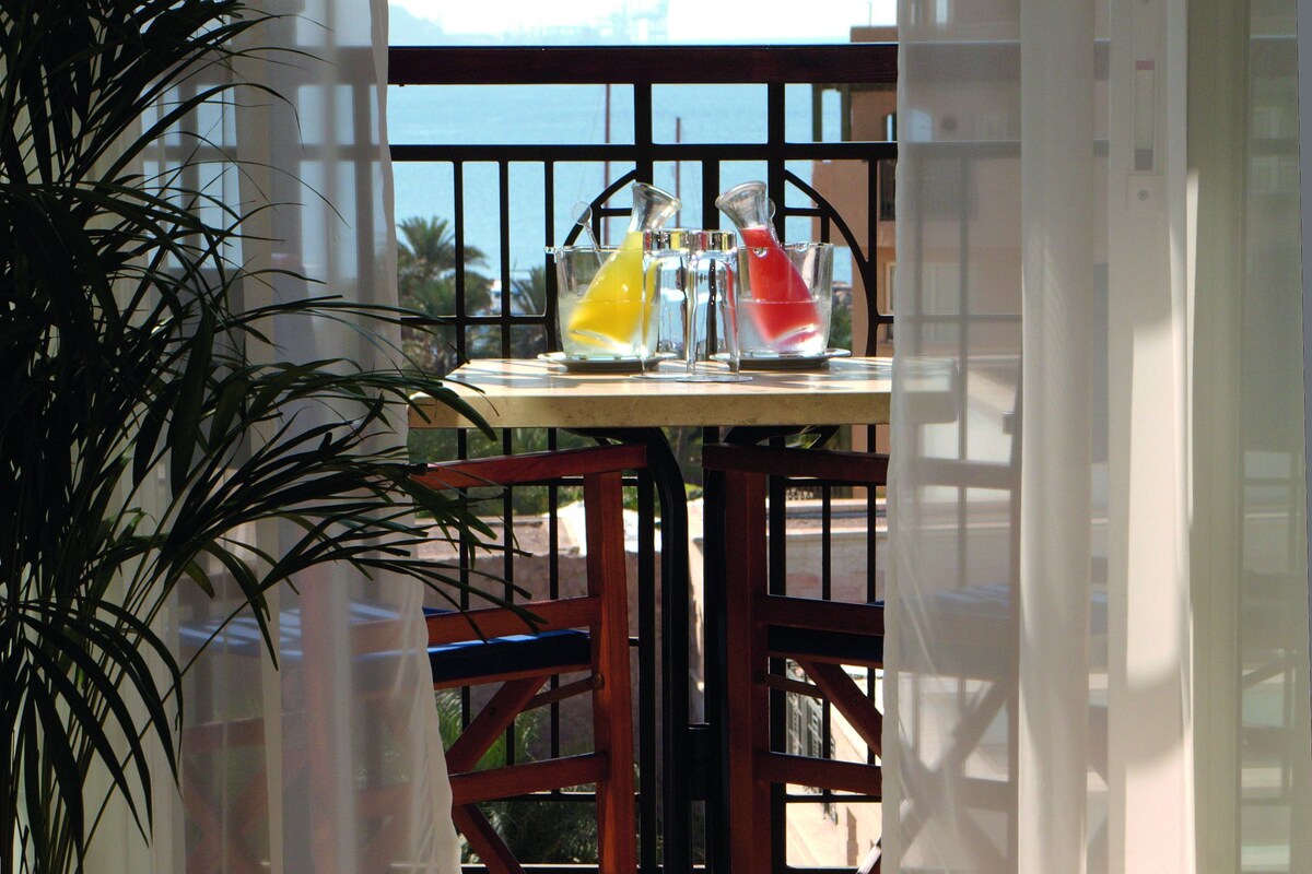 A balcony with a table, chairs, and a potted plant.