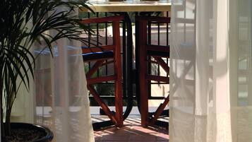 Un balcon avec une table, des chaises et un pot de fleurs.