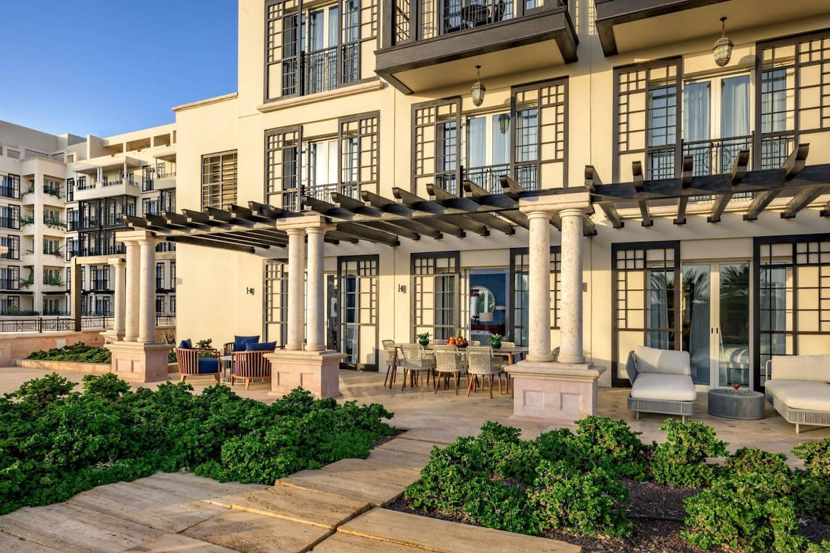 A multi-story building with balconies, outdoor seating, and a garden area.