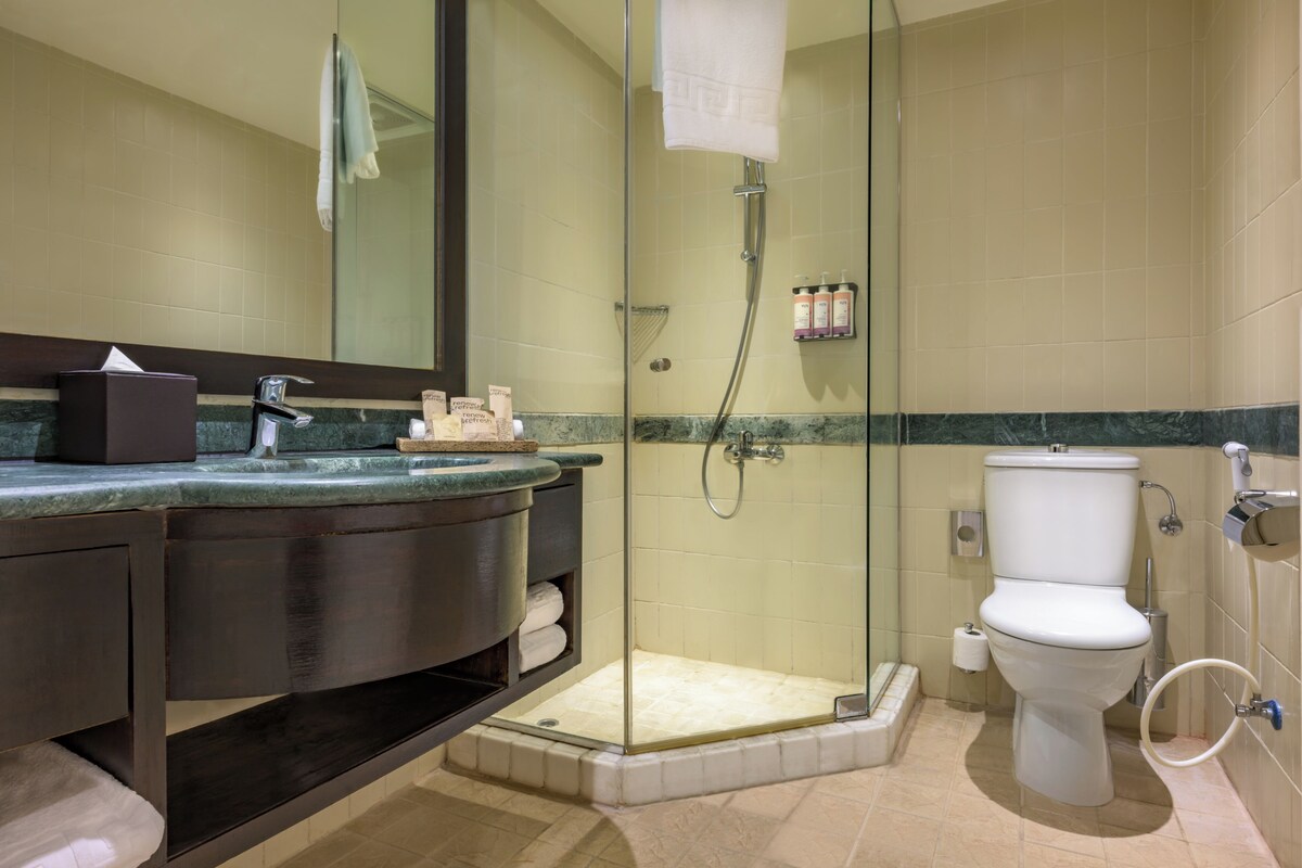 A bathroom with a glass-enclosed shower, a toilet, and a vanity with a mirror.