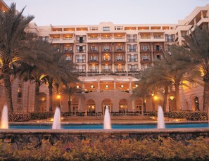 A multi-story hotel with a central courtyard, palm trees, and a pool with fountains. - Mövenpick Resort & Residences Aqaba (Aqaba)