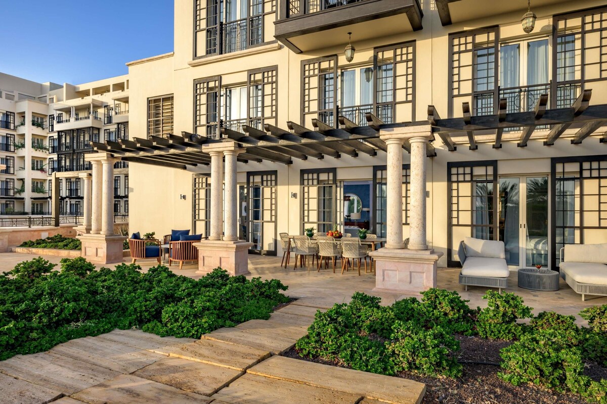 A multi-story building with balconies, outdoor seating, and a garden area.