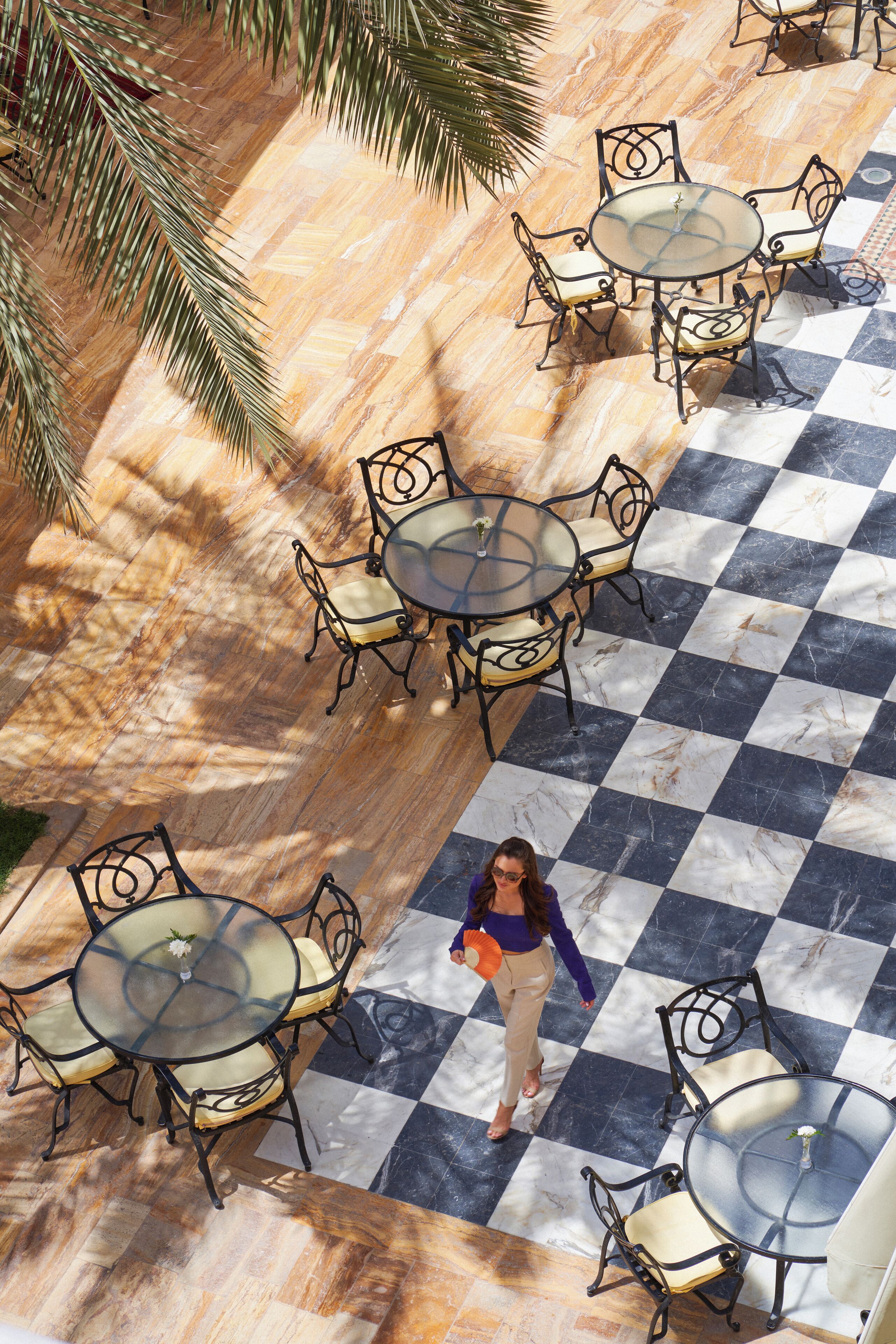 Un patio al aire libre con suelo a cuadros y mesas redondas con sillas.