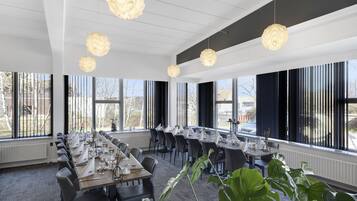 Une salle de conférence dotée de longues tables, de chaises et de grandes fenêtres.