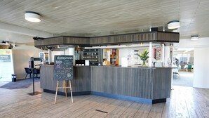 A reception area with a counter, a chalkboard with information, and a seating area with chairs. - Østergaards Hotel (Herning)