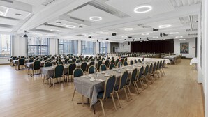 A large conference room with multiple tables and chairs, high ceilings with exposed beams, and large windows allowing natural light. - Østergaards Hotel (Herning)